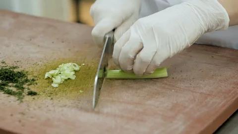 Close up of chef slicing fresh celery sticks on a wooden chopping board Stock Footage 106186833