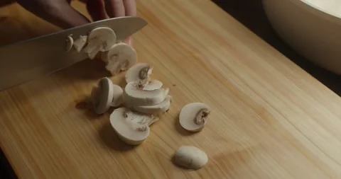 Close-up of a chef slicing fresh white mushrooms on a wooden cutting board Vídeo Stock 328338047