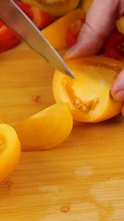 Close-up of a chef slicing a fresh yellow tomato. Stock Footage 341510047