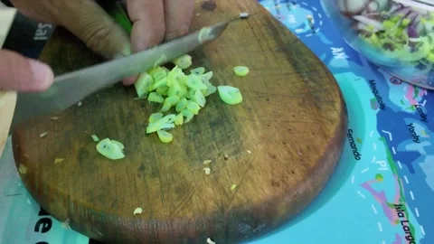 Close-Up of Chef Slicing Green Onions on a Rustic Wooden Cutting Board Stock Footage 343066383