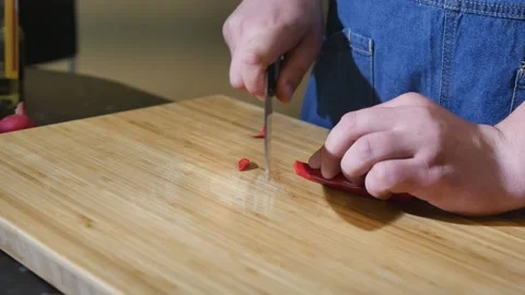 Close-up of a chef slicing hot chili peppers on a cutting board Stock Footage 201102347
