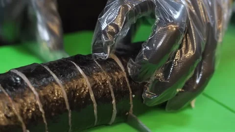 Close-up of Chef Slicing Kimbap Roll Wrapped in Plastic Wrap Stock Footage 333570460