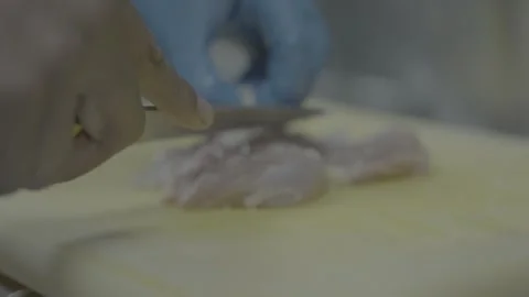 Close-up of chef slicing raw chicken breast with a sharp knife Stockbeeldmateriaal 327356423