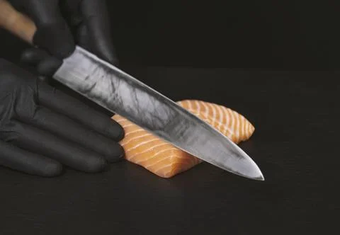 Close up of chef slicing salmon with sharp knife on black desk Stock Photos