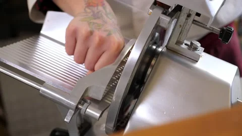 A close-up of a chef slicing sausage using an industrial meat slicer. Stock Footage 307389372