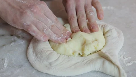 Close-Up of Chef Spreading Cheese Filling on Dough for Adjarian Khachapuri Stock Footage 288575791