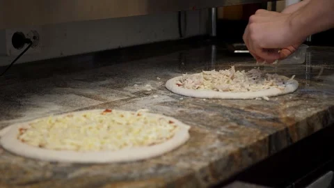 Close-up of the chef spreading chicken meat and mushrooms on a cheese pizza. Stock Footage 307389857