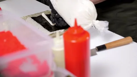 A close-up of a chef spreading cream cheese on rice and nori. Stock Footage 323363755