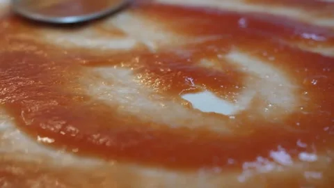 Close-up of Chef Spreading Fresh Tomato Sauce on Homemade Pizza Dough with a Spo Stock Footage 337678468