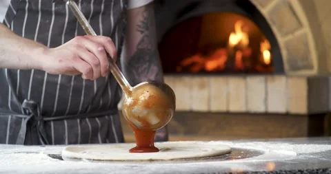 Close Up of Chef is spreading Tomato Sauce on Pizza Dough with a Metal Ladle. Stock Footage 132984397
