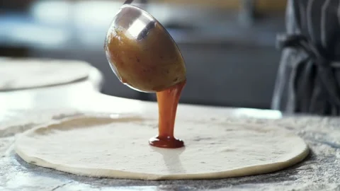 Close Up of Chef is spreading Tomato Sauce on Pizza Dough with a Metal Ladle. Stock Footage 132985130