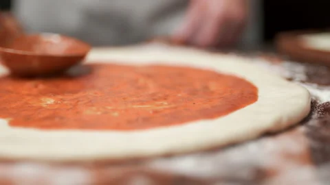 Close-up of chef spreading Tomato Sauce on pizza dough with a ladle in 4K. Stock Footage 137481840