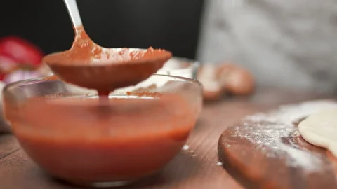 Close-up of chef spreading Tomato Sauce on pizza dough with a ladle in 4K. Stock Footage 137481861