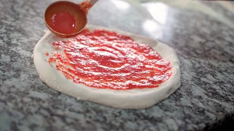 Close-up of chef spreading tomato sauce on pizza dough. slow motion video Stock Footage 231336607