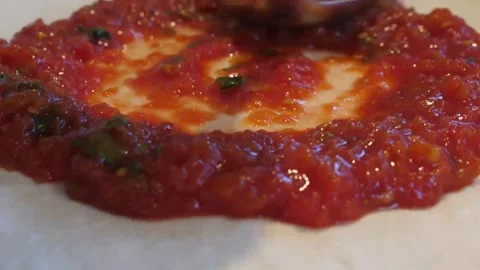 Close-up of Chef Spreading Vibrant Red Tomato Sauce on Fresh Pizza Dough with La Stock Footage 337677395