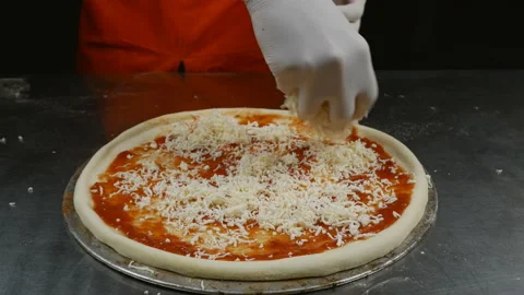 Close-up of a chef sprinkling cheese on pizza dough Video stock 144428255