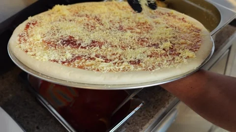 Close-up of a chef sprinkling grated cheese on a pizza in a restaurant kitchen. Stock Footage 341550226