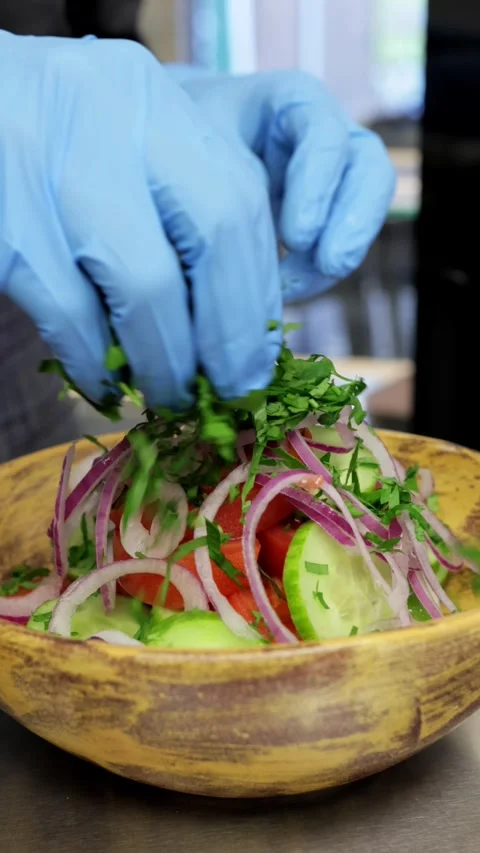Close-up of Chef Sprinkling Vegetable Salad with Herbs, Vertical Video Stock Footage 288577923