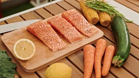 Close-up. The chef squeezes a lemon by sprinkling a salmon steak before frying Video stock 198200536