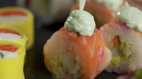 Close up chef squeezing green cream on fresh salmon sushi roll Stock Footage 340546223