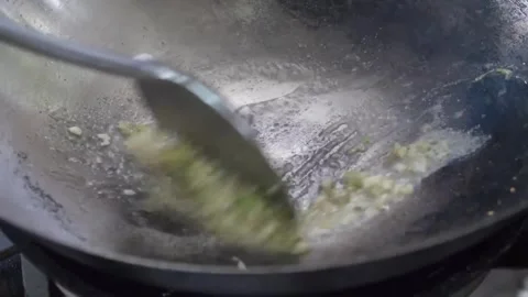 Close-up of Chef Stir-Frying Minced Garlic and Ginger in Hot Wok Stock Footage 338211794
