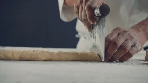 Close-up chef on the table cuts the dough into pieces. 4K slow motion video Stock Footage 105352495