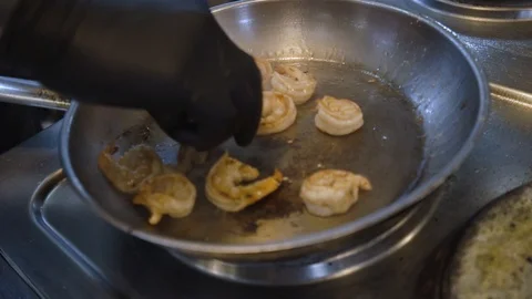 Close up chef tossing frying pan with shrimp. Hissing shrimp in frying pan Stock Footage 105271944