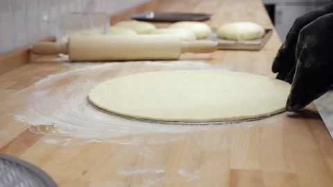 Close-up of the chef tossing the pizza dough and placing it on a baking tray. 库存影片 339787518