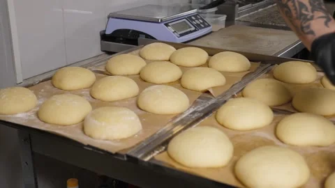 Close-up of the chef using a brush to apply egg mixture to round burger buns. Stock Footage 342702151