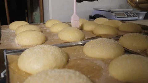 Close-up of the chef using a brush to apply egg mixture to round burger buns. Stock Footage 343736279