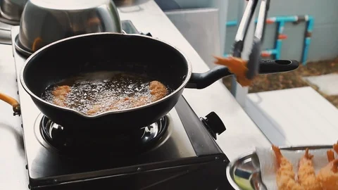 Close up of chef using metal tongs to take deep fried shrimp out of oil in pan Video stock 113383198