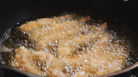 Close up of chef using metal tongs to flip deep fried shrimp in pan with hot oil Stock Footage 113383468