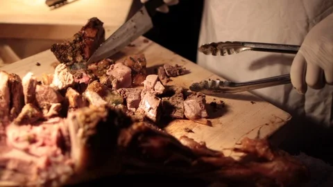 Close up of chef using tongs to move fresh cuts of cooked pork 動画素材 100736730