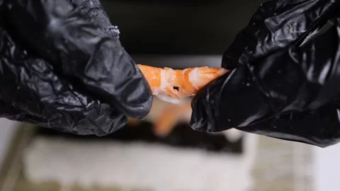 Close-up of a chef wearing gloves peeling and cracking a shrimp in a kitchen. Stock Footage 327273783