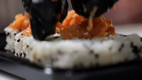 Close-up of a chef wearing gloves putting sliced salmon on sushi before baking. Stock Footage 323911059