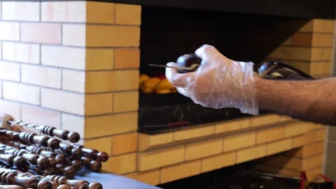 Close-up of a chef wearing gloves stringing eggplant on a skewer in a restaurant Stock Footage 320877959
