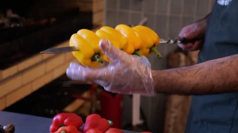 Close-up of a chef wearing gloves stringing peppers on a skewer before grilling Stock Footage 320877987