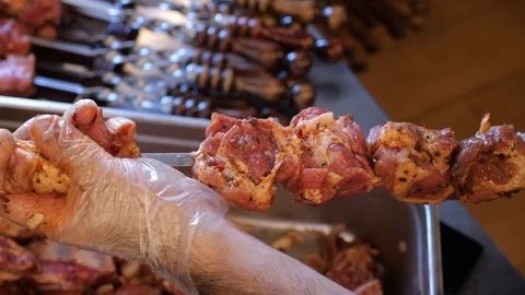 Close-up of a chef wearing gloves stringing marinated pork meat on a skewer. Stock Footage 321815460