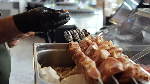 Close-up of a chef wearing gloves stringing marinated pork meat on a skewer. Stock Footage 341316848