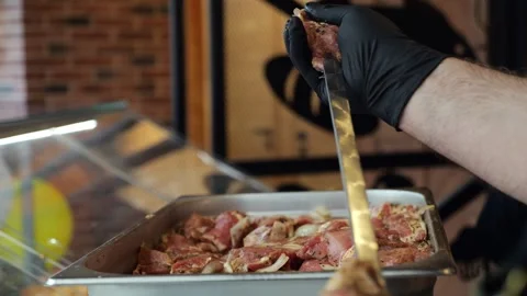 Close-up of a chef wearing gloves stringing marinated pork meat on a skewer. Stock Footage 341550631