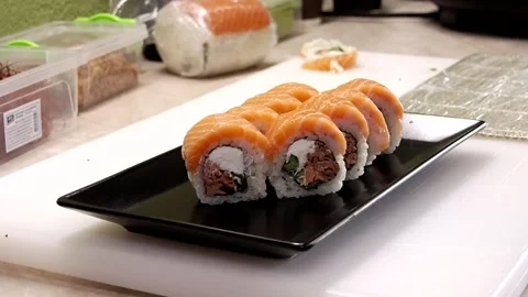 Close-up of chef wearing gloves transferring sushi to black plate in video Stock Footage 285248538