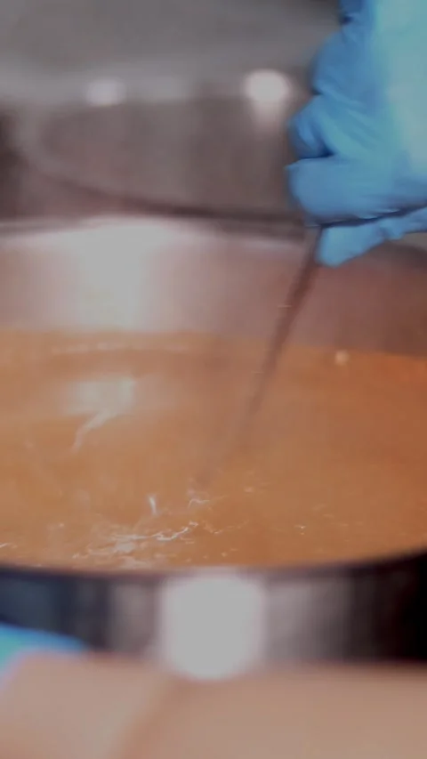 Close-up. Chef wearing protective gloves is stirring tomato soup or borscht with Stock Footage 321753630