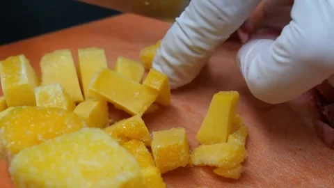Close-Up of Chef in White Gloves Dicing Fresh Mango on a Cutting Board Stock Footage 345652643