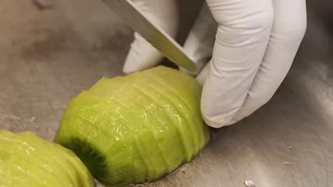 Close-Up of Chef in White Gloves Slicing a Peeled Avocado Half on a Metal Surfac Stock Footage 331778564