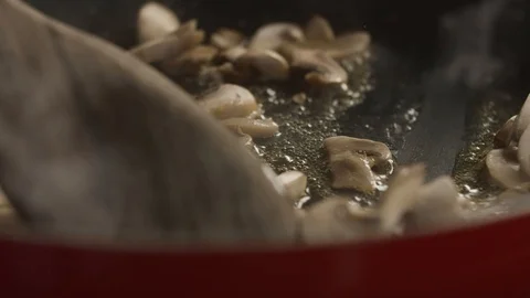 Close-up of chef with wooden spatula interferes with chopped champignon in pan Stock Footage 113741535