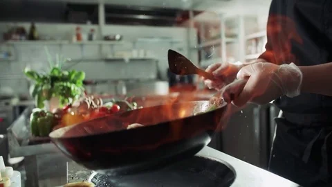 Close-up of a chef working the wok with flames roasting mixed colorful Stock Footage 77984353
