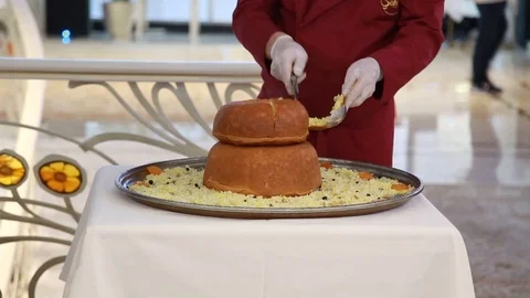 Close-up of a chef's chef cutting a knife firm dish - pilaf baked in bread Stock Footage 99366855