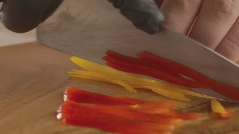 Close-up of chef's hand chopping bell pepper with sharp knife. Slow motion video Stock Footage 114863142