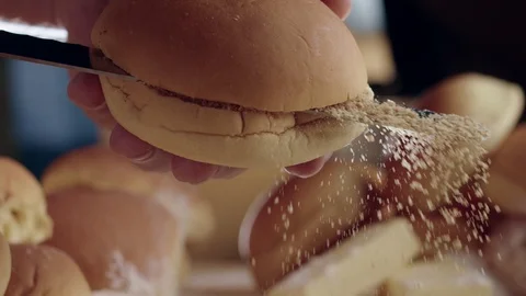Close-up of chef's hand cutting burger bun in half with sharp knife Stock Footage 111750090