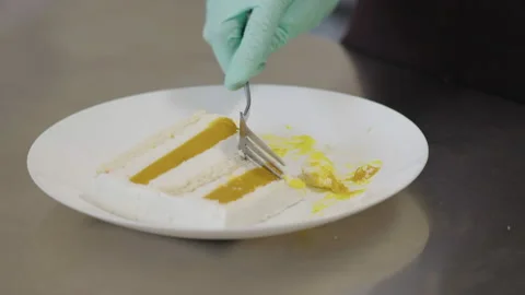 Close-up, Chef's Hand in Glove with Fork Tastes Piece of Cake on White Dish Stock Footage 136952482